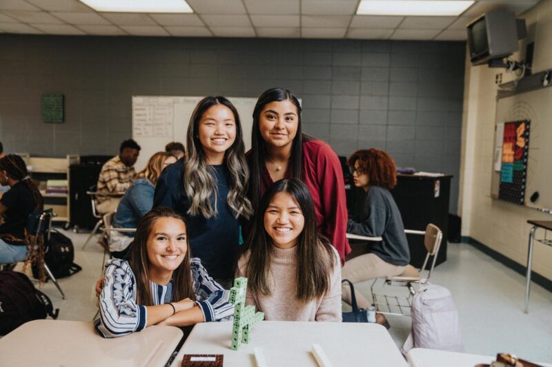 Group of female students smile while in classroom