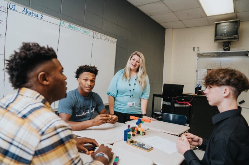 Teacher and students talk around a table