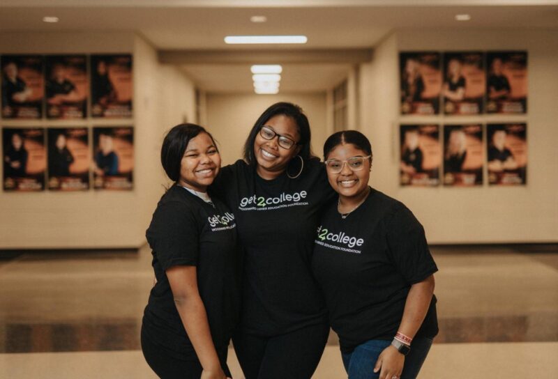 three students smiling wearing black get2college shirts